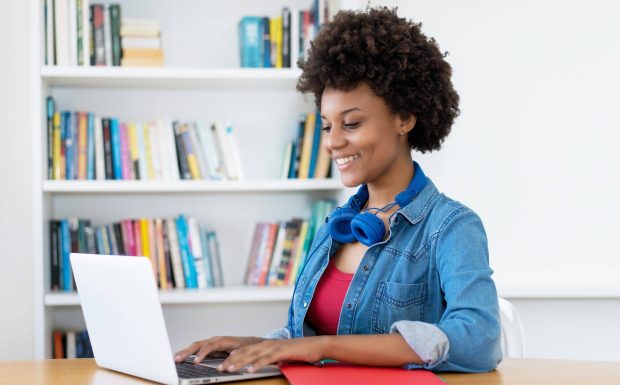Beautiful african american young adult woman at computer indoors at desk at home